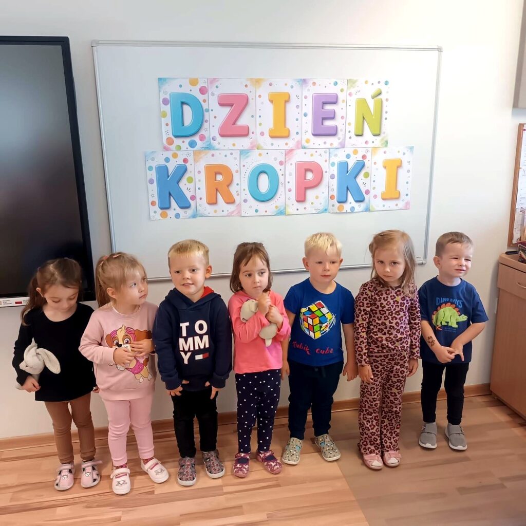 Przedszkolaki stoją przed napisem „Dzień Kropki”