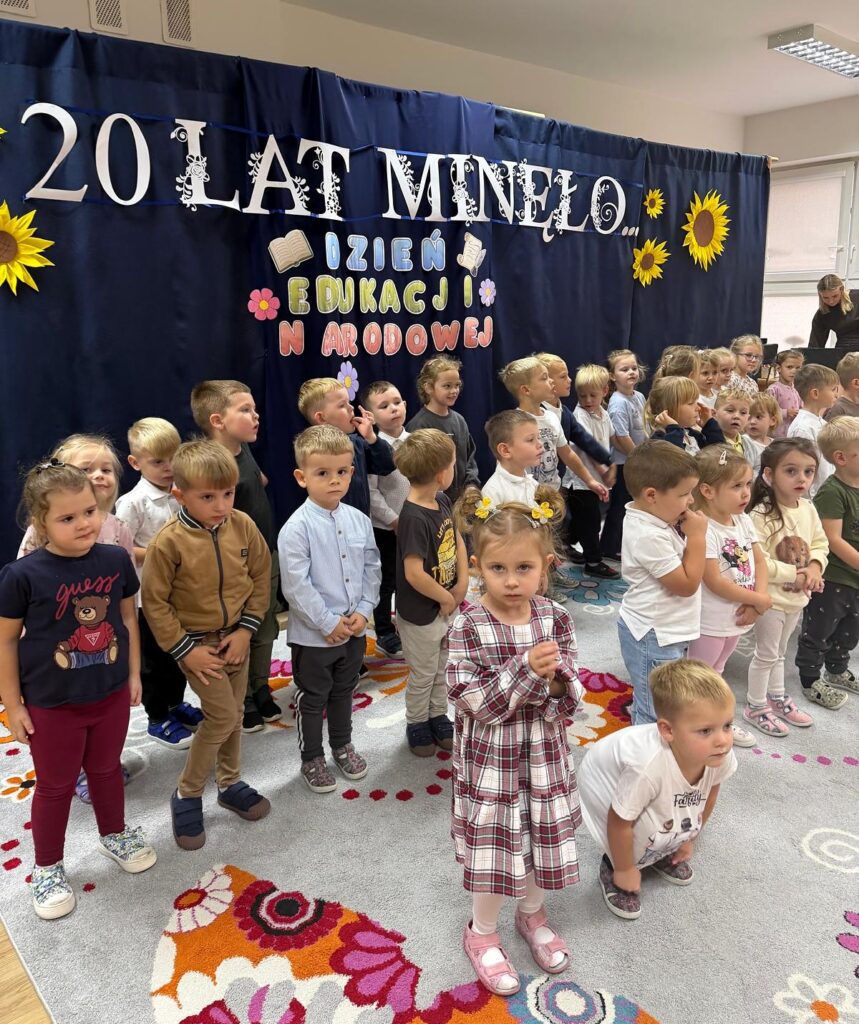 Dzieci śpiewają przed dekoracją przygotowaną na Dzień Edukacji Narodowej.