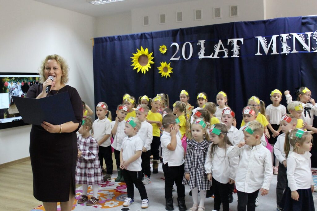 Wystąpienie podczas jubileuszu na tle dzieci i dekoracji 20 lat minęło.